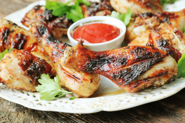 istock Grilled chicken legs on wooden table served on white plate with coriander 815503318