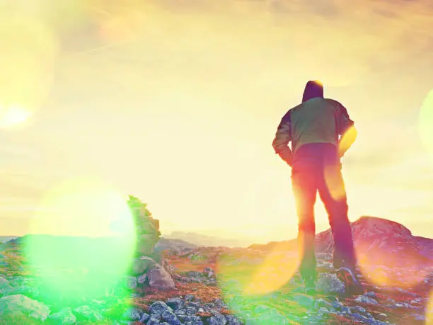 Photo of Film grain effect.   Tourist guide at stocked stones on Alps peak. Strong hiker enjoy sunset