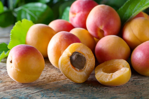 istock Juicy fresh apricots with leaves on old wooden table . 815553992
