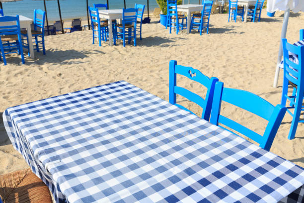 istock Picnic table with white and blue table cloth by the sea in Greece, Empty picnic table for product display, Defocused beach in the background 815570436