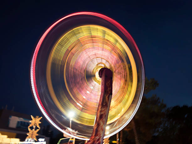 carrousel lumineux dans le parc de la soirée - ferris wheel wheel blurred motion amusement park photos et images de collection