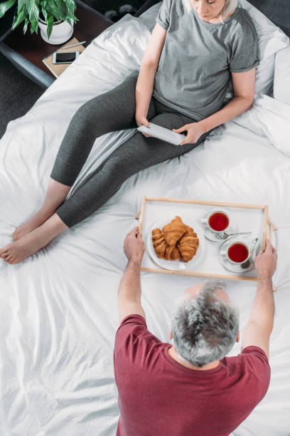 istock overhead view of man brought breakfast in bed while woman using tablet 815588102