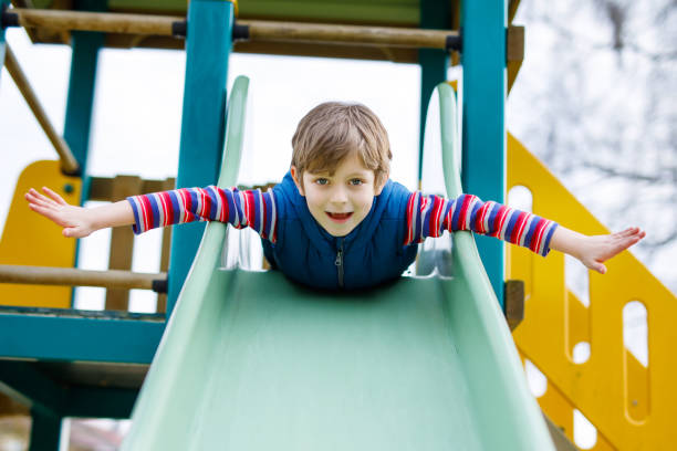 istock Happy blond kid boy having fun and sliding on outdoor playground 815595000