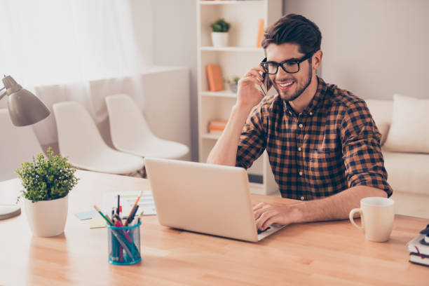 istock Young freelancer working with laptop and talking on phone with client 815601560