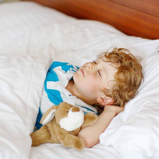 istock Little blond child sleeping in his bed with toy. 815606504