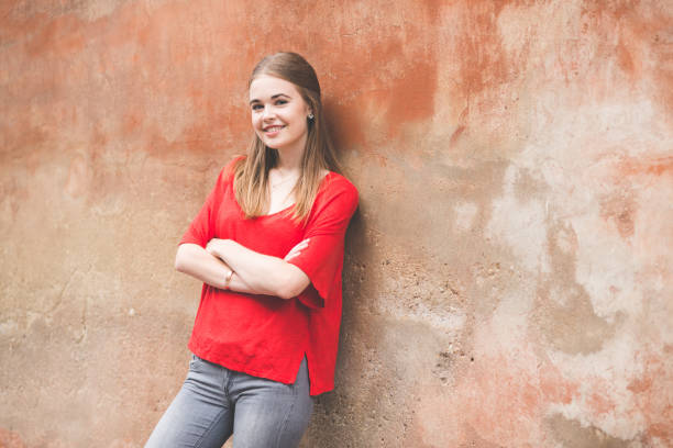istock confident young woman standing against wall 815607036
