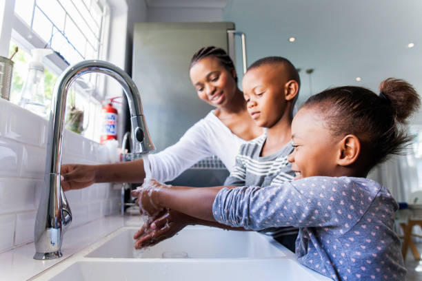 Family washing their hands together. African mother opening the tap for her kids to wash their hands in the kitchen. african ethnicity south africa fitness stock pictures, royalty-free photos & images