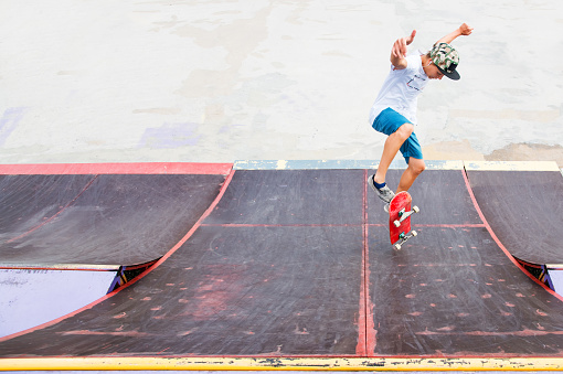 Young boy doing a trick with a jump on the ramp in the skatepark. Photo with a place for copy-space