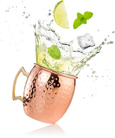 splashing moscow mule cocktail in copper mug isolated on white