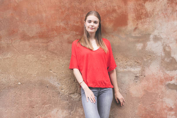 istock confident young woman standing against wall 815625102