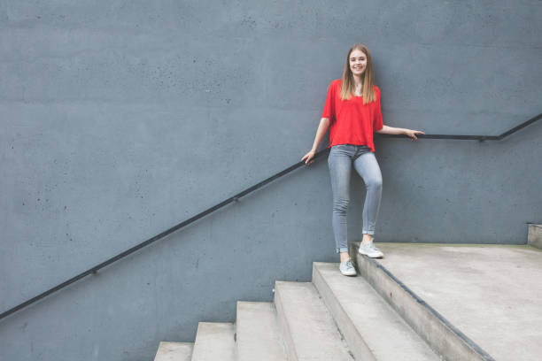 istock confident young woman standing against wall 815629958