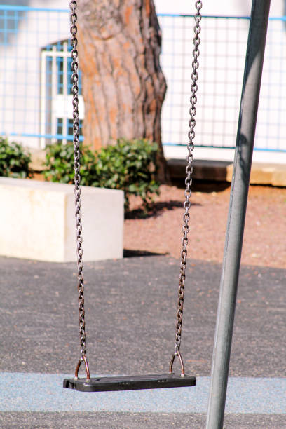 istock Swing in city park. Empty chain swing in children playground. 815635006