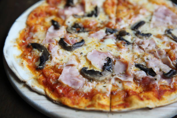 istock pizza ham and mushroom on wood 815635296