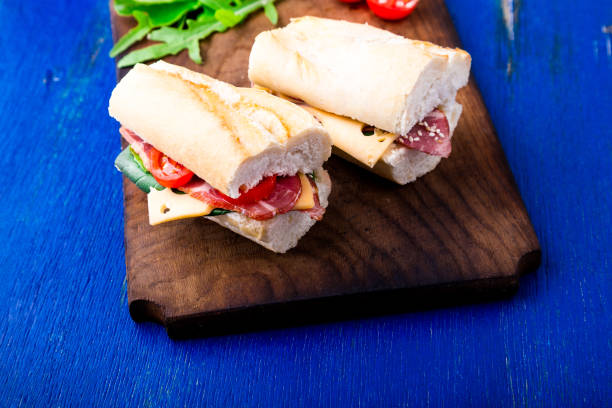 istock Sandwich with jamon, arugula, tomatoes, cheese on wooden board blue background. Rustic. Two. 815646336