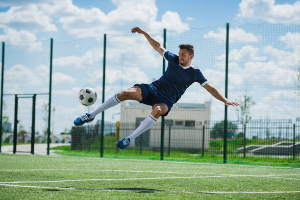 istock athletic soccer player kicking ball on soccer pitch 815653964