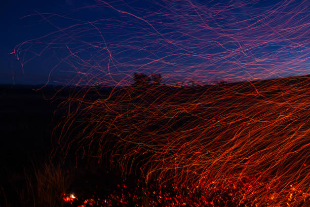 A slow shutter speed makes this fire appear distorted with the sparks stretching out into lines. This is shot against a twilight sky.