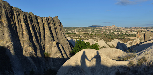 Couple shadow on illuminated rock. Landscape in background. Place - Cappadocia (Turkey).