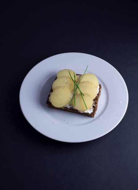 istock Danish open faced sandwich with potatoes on white plate with black background 815678130