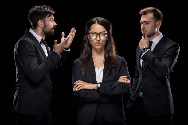 istock confident businesswoman looking at camera while her colleagues discussing something behind, isolated on black 815680898
