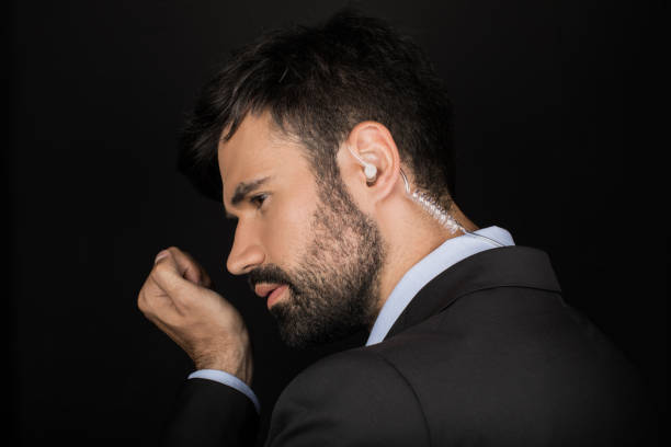 istock Secret service agent in suit using earphone, isolated on black 815686328