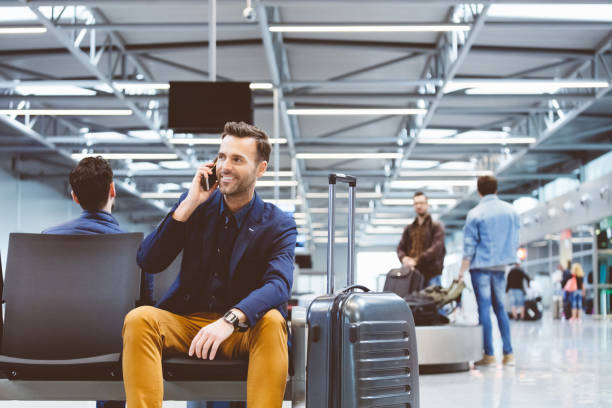 hombre en el salón del aeropuerto y el uso de teléfono móvil - airport waiting room waiting airport lounge fotografías e imágenes de stock