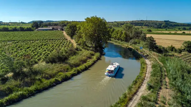 Aerial top view of boat in Canal du Midi from above, family travel by barge and vacation in Southern France