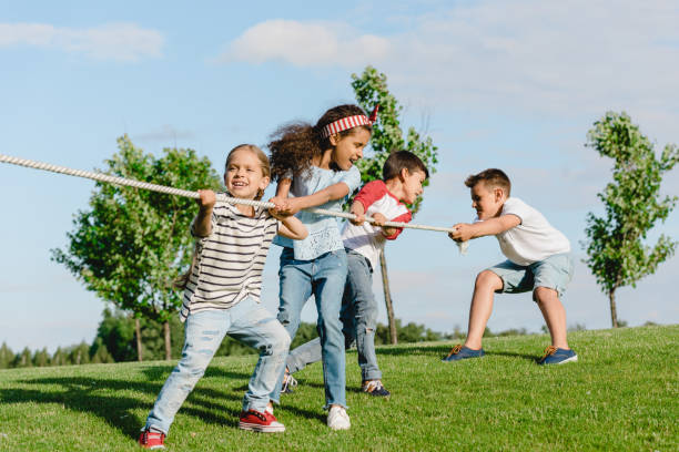 istock Cheerful multiethnic kids pulling rope and playing tug of war in park 815702938