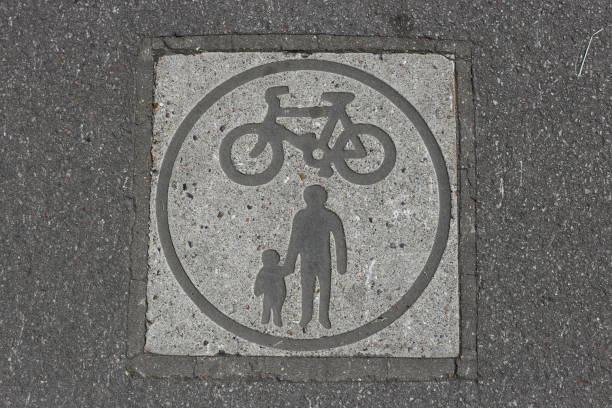 A signal embedded in asphalt marking a bike and pedestrian route in the park.