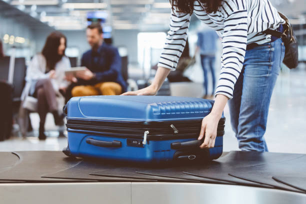 viajero mujer escogiendo encima de la maleta de la línea de reclamo de equipaje - luggage fotografías e imágenes de stock