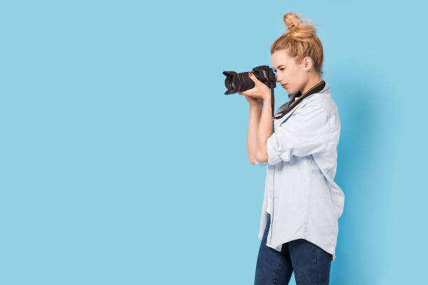 Young blonde photographer is taking a photo. stock photo