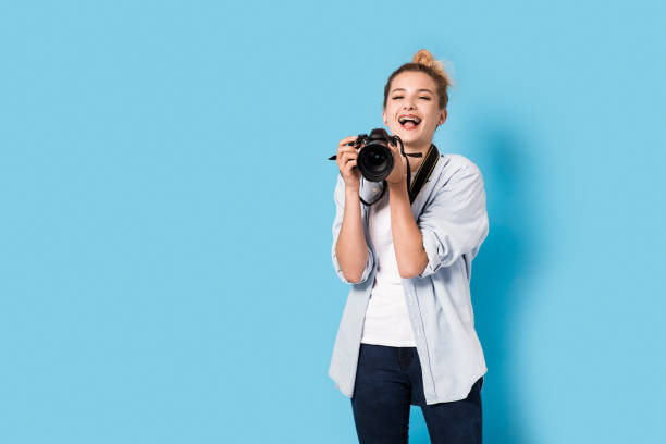 istock Young blonde photographer is enjoying her work. Model isolated on a blue background with copy space 815730610