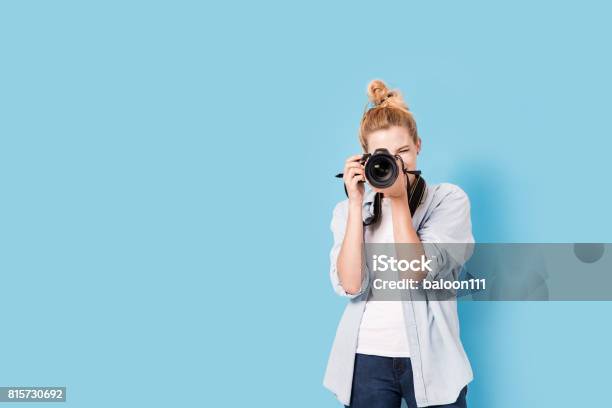 Young Blonde Photographer Is Taking A Photo Model Isolated On A Blue Background With Copy Space Stock Photo - Download Image Now