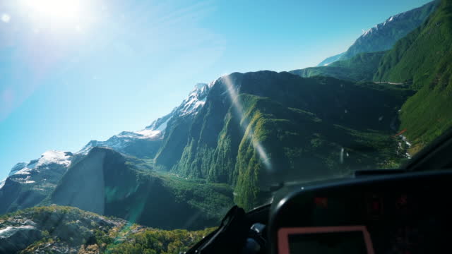 View out of helicopter cockpit over mountains at sunrise