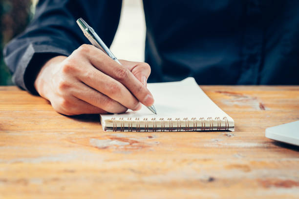 istock Hand business man writing notebook on wood table in coffee shop. 815741408