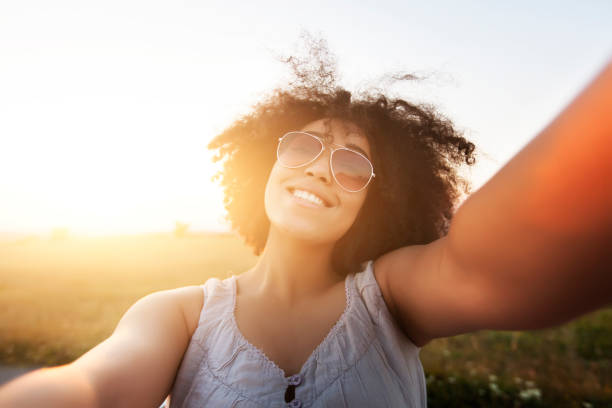 istock Young woman having fun at sunset, taking selfie 815743294