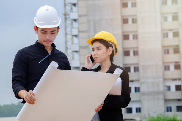 istock Project maneger check building blueprint with his secretary in front of building site, Engineer checking work for control on site concept. copy space 815762258