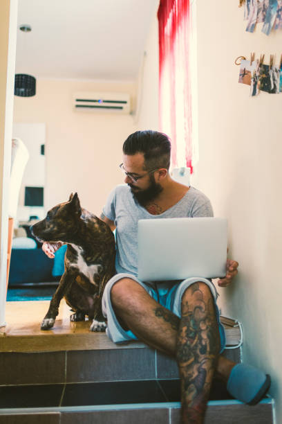 istock Man using laptop at home with his dog next to him 815792358