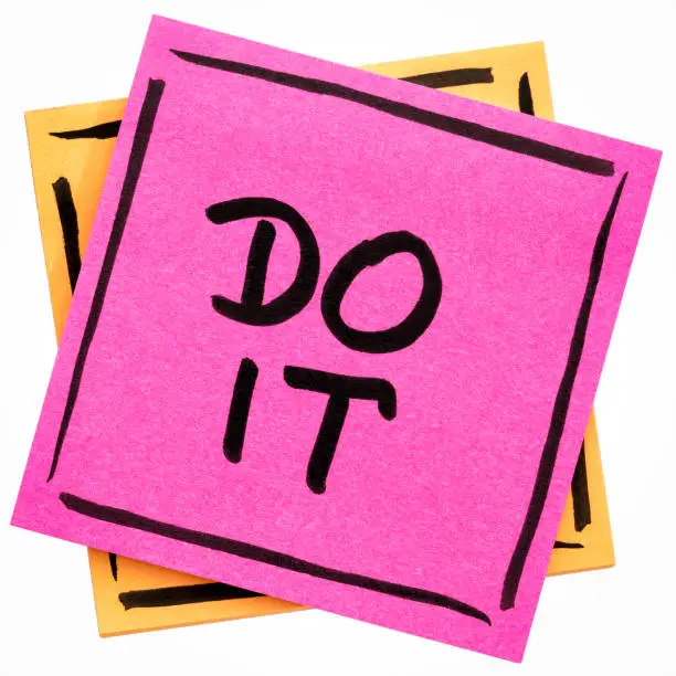 Do it motivational reminder - handwriting in black ink on an isolated sticky note