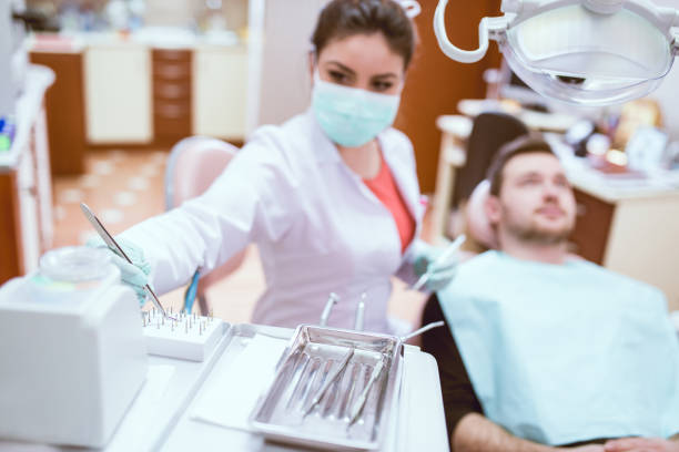 istock Female Dentist With Instruments Examining Young Male Patient 815839264