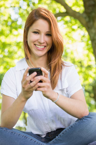 istock Pretty redhead sending a text in the park 815862520