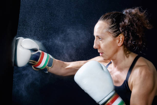 A boxer woman throws a fist. Fist in the sack. A boxer woman throws a punch in the sack. Splashes of water and sweat on the black background. slenderman fictional character stock pictures, royalty-free photos & images