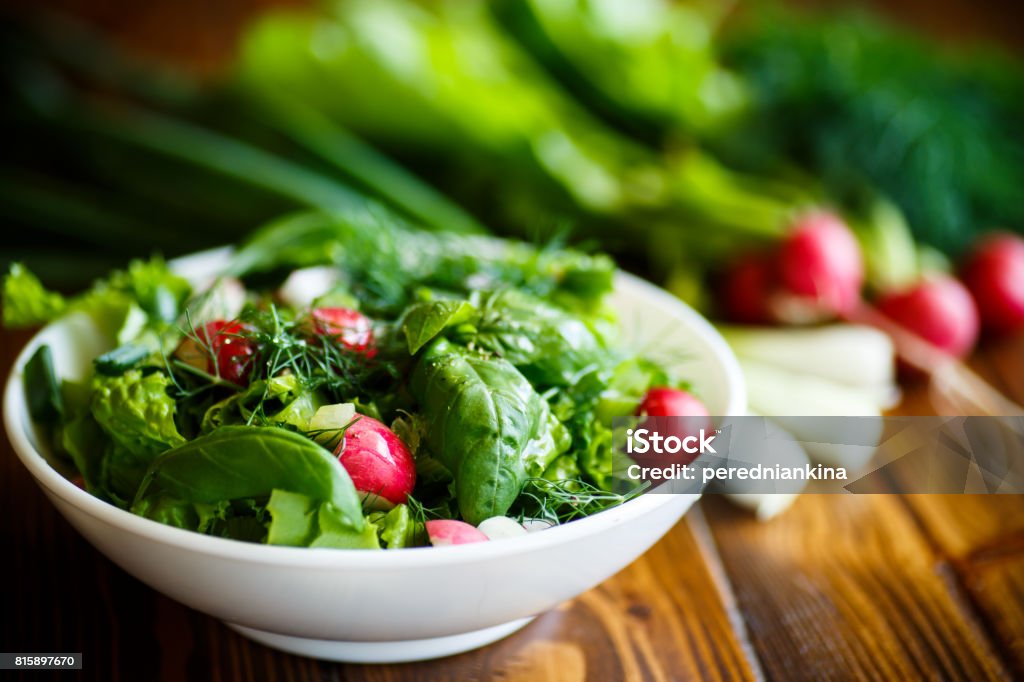 Spring salad from early vegetables, lettuce leaves, radishes and herbs Spring salad from early vegetables, lettuce leaves, radishes and herbs in a white bowl Salad Stock Photo