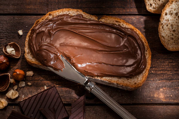 istock Chocolate and hazelnut spread on bread slice shot on rustic wooden table 815897716