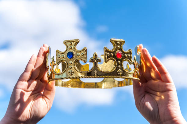 istock Gold crown with stones in hands against the blue sky 815901018