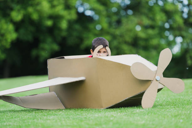 istock Cute little boy pretending to be pilot sitting in diy airplane while playing in park 815903668