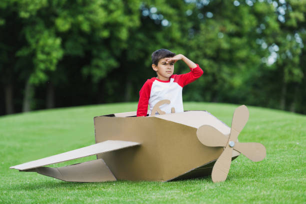 istock Cute little boy pretending to be pilot sitting in diy airplane while playing in park 815903710