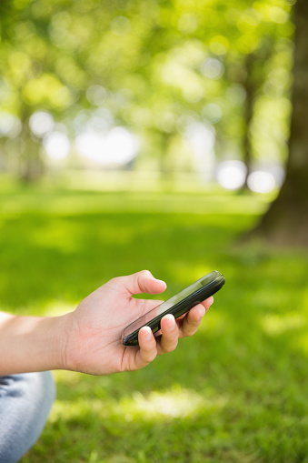 Enviar un texto en el teléfono inteligente en el parque de la mujer photo