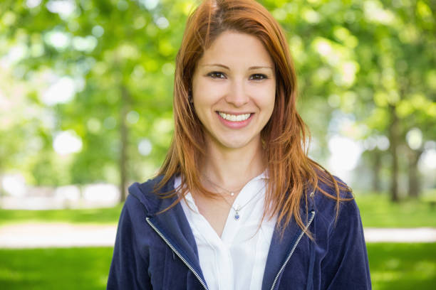 istock Pretty redhead smiling at camera in the park 815934710