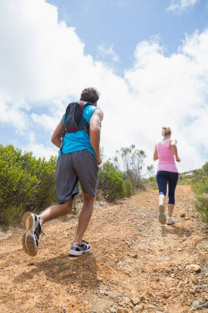 fit attractive couple jogging up mountain trail - running jogging footpath cross country running imagens e fotografias de stock