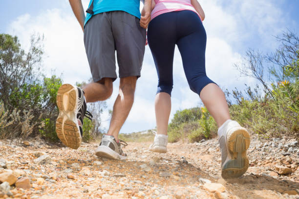 fit couple running up mountain trail - running jogging footpath cross country running imagens e fotografias de stock